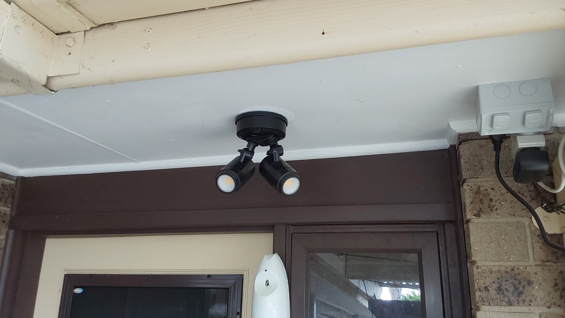 A pair of black LED spotlights mounted under the verandah eaves